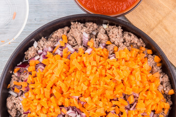 Minced meat with onions and carrots for bolognese sauce roasted in a frying pan