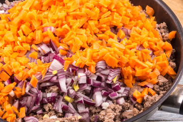 Minced meat with onions and carrots for bolognese sauce roasted in a frying pan
