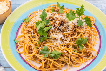 Spaghetti bolognese with cheese and celery leaves - top view