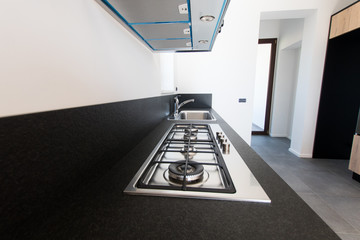 island of a black granite kitchen with the detail of the hob with the steel stove. detail of the...