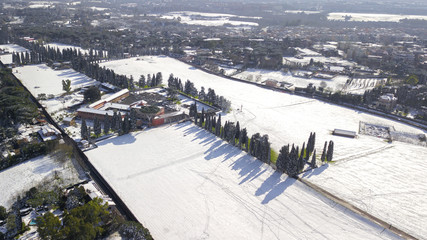 Aerial view of the aqueduct park in Rome, Italy. The park is covered by snow and ice on a cold winter day. Some small houses can be seen on the lawn.