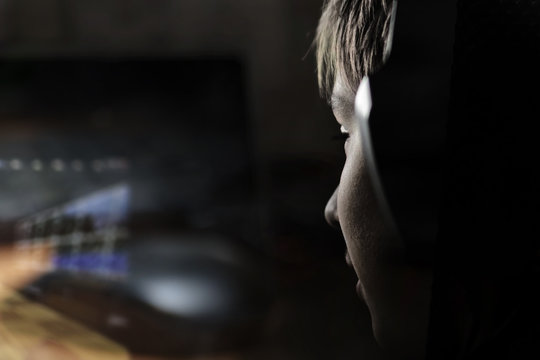 Close up of young boy staring at laptop screen during playing computer games