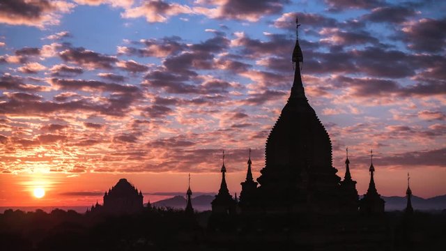 Bagan, Myanmar (Burma), time lapse view of hot air balloons flying over ancient temples and pagodas at sunrise.
