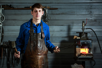 Young muscular man working on a blacksmith with metal