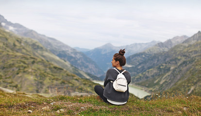 young woman tourist on a background of mountainous natural scenery sits on the edge of the cliff