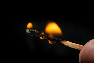 brennendes fast abgebranntes Streichholz mit Flamme vor schwarzem Hintergrund