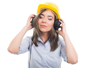 Portrait of female constructor listening to headphone.