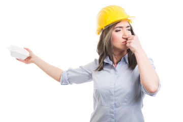 Portrait of female constructor covering nose from lunch box.