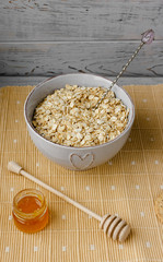 Healthy breakfast: oatmeal cereal, cup of milk, jar of homemade jam, oatmeal cookies. Flowers in a vase on a background. Coconut biscuits on a saucer. Exquisite romantic breakfast. Food blog ideas