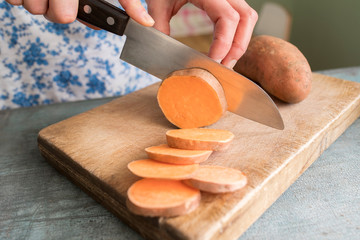 Close Up Of Woman Preparing Sweet Potato On Chopping Board