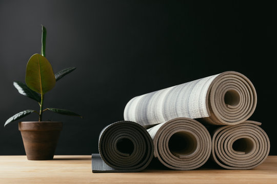 different rolled yoga mats and potted plant on wooden table