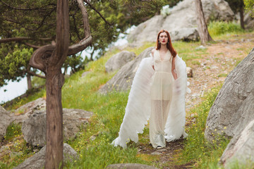 Girl with white wings wander in the woods