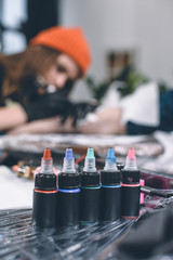 Bottles of ink in front of working tattoo master