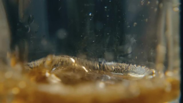 Coca-Cola is poured from a can of red color against a dark background. Slow-motion close-up shooting