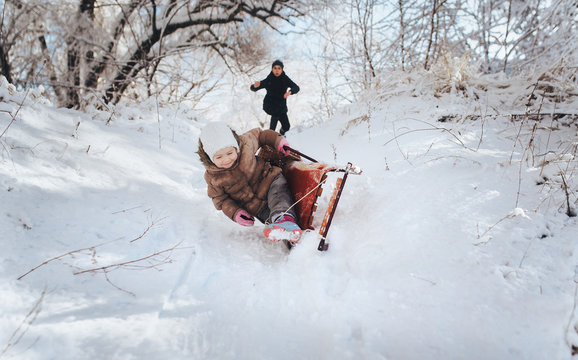 The little girl is falling from the sleigh. Mother worries about the child and runs to help her. Extreme, adrenaline, danger. Mom's reaction to the fall of her child. Sledding in the winter forest.