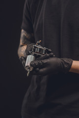 Fototapeta na wymiar Tattoo machine in male hands isolated on black