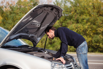 A man tries to repair the car on the road