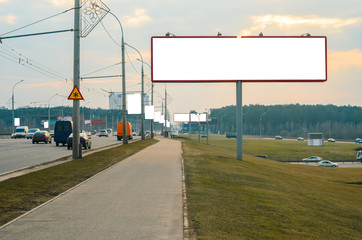 Blank white billboard on the highway on the background of sunset with cloudy sky, mock up