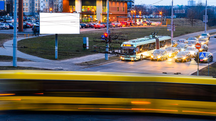 Blank billboard on night city street, mockup. Light trails from passing cars through the streets of the night city.