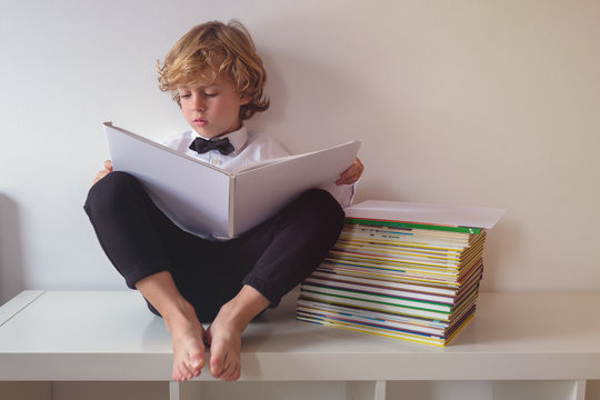 Boy sitting on table and reading book