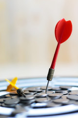 Red dart arrow hit the center target of dartboard and money coin metaphor marketing or saving money...