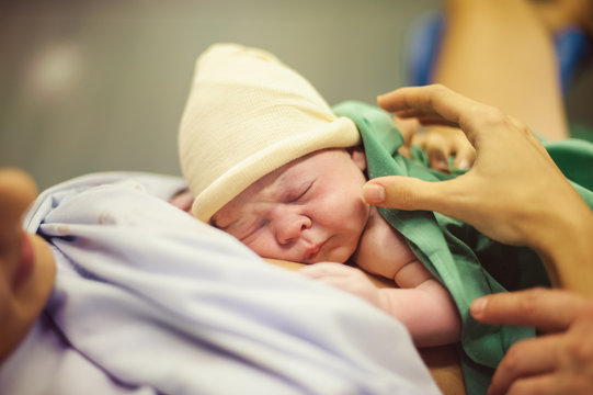 Hands embracing newborn child