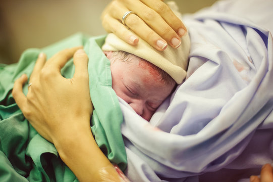 Hands embracing newborn child