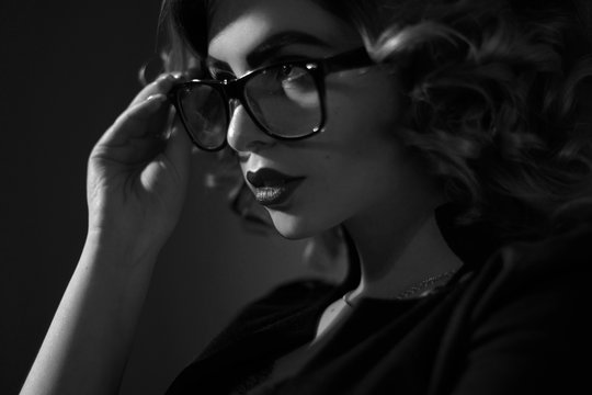 black and white photo of Sexy young secretary in glasses and curly hairstyle