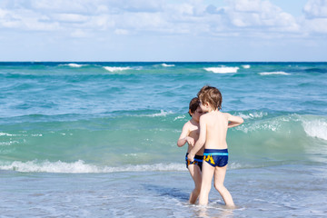 Two kid boys running on ocean beach. Little children having fun