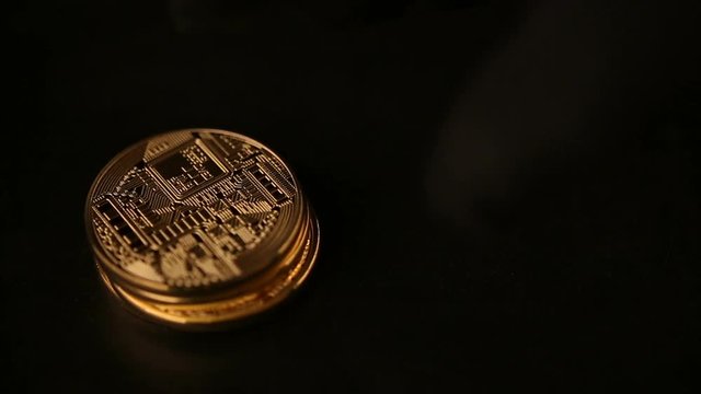 Gold coins bitcoin stacked in a pile on black background