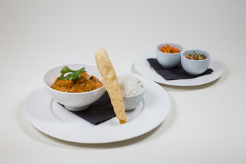 Indian Curry in a white bowl with rice on a white plate on a white background isolated