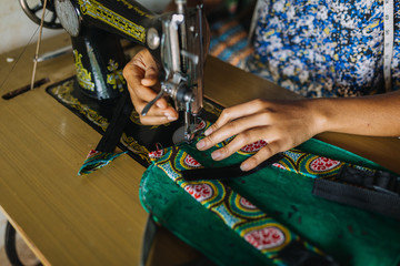 african woman sewing a bagpack close up