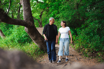 Naklejka na ściany i meble Senior couple walking together in a forest, close-up