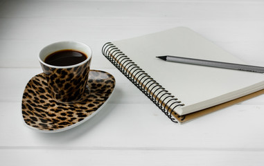 Business planner with pencil on a white wooden table. Cup of espresso coffee and notebook with list...
