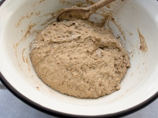 Preparation of the homemade bread dough/
Traditional dough preparation for homemade bread. Hand mixing with a wooden spoon in the enameled metal bowl. Slant top view, close-up.