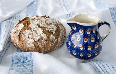 Freshly baked homemade bread with the milk jug/
Fresh homemade round loaf of bread with the ceramic milk jug. Slant top view.