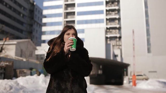 Girl winter in the city drinking coffee from a green Cup