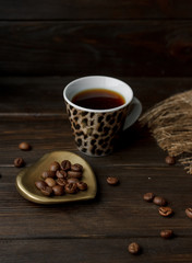 Table composition of vintage copper Turkish coffee pod with a wooden handle, 100% pure arabica roasted beans and espresso on a brown tablecloth. Perfect morning ideas for coffee lovers