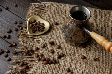 Table composition of vintage copper Turkish coffee pod with a wooden handle, 100% pure arabica roasted beans and espresso on a brown tablecloth. Perfect morning ideas for coffee lovers