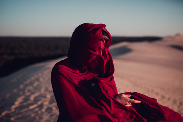 Woman sitting on sand dune in desert