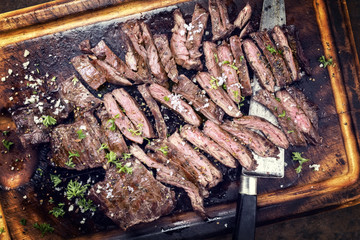 Traditional barbecue skirt steak sliced as close-up on a wooden board