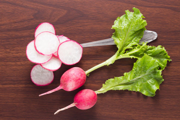 Radish cut into pieces with greens on a dark wooden background