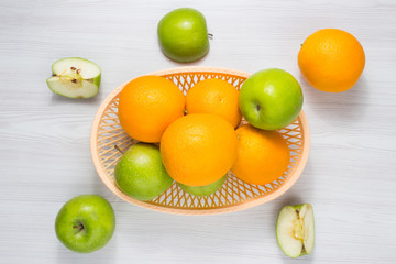 Green apples and oranges on wooden table. Fruits