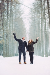 guy and girl walking and having fun in the snowy forest