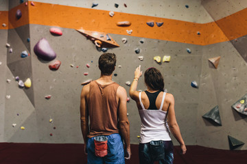 Man and woman at an indoor rock climbing gym - obrazy, fototapety, plakaty