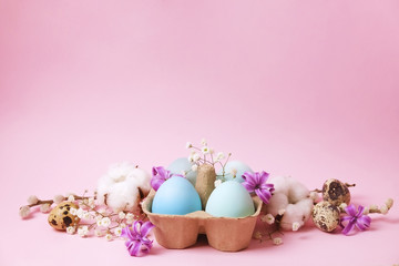 Traditional easter card template with pastel colors painted organic eggs in wicker basket with hay and decorative wildflowers.
