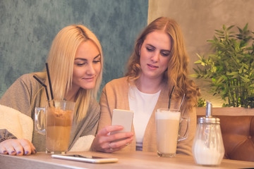 Young beautiful girls sitting in face and using mobile phone.