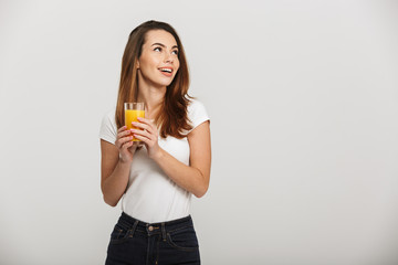 Cheerful young lady looking aside drinking juice.