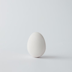 Minimal white Easter egg on bright background.