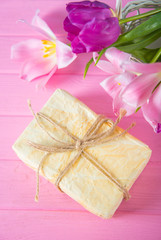 Crafted gift box and tender bouquet of beautiful pink tulips on pink wooden background